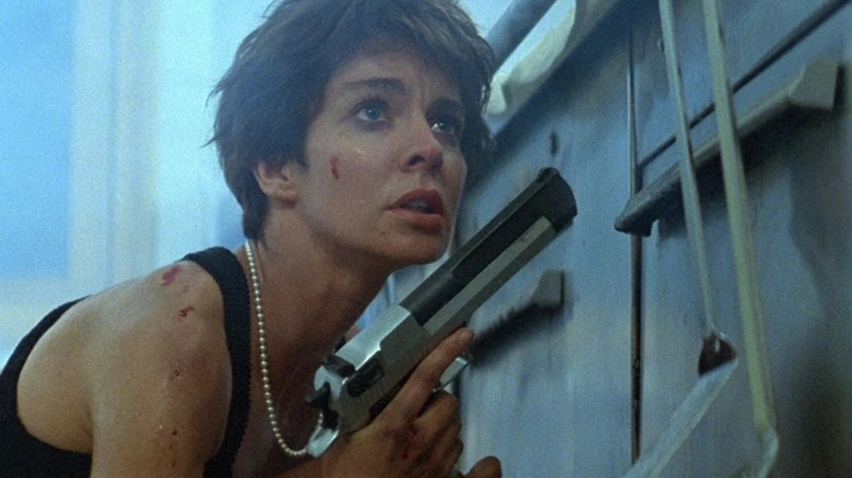 Nikita hides behind a dumpster with a gun in La Femme Nikita