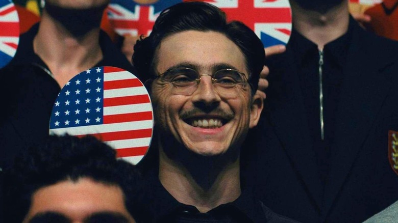 Marty holding up a paddle with the American Flag in Marty Supreme