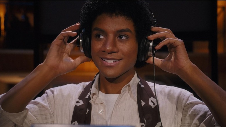 Michael smiling and adjusting his headphones in Michael (2026)