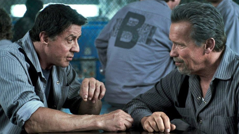 Breslin and Rottmayer sitting at a table in prison in "Escape Plan" (2013)