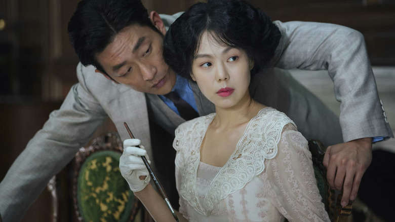 Count leaning over Lady Hideko from behind in The Handmaiden