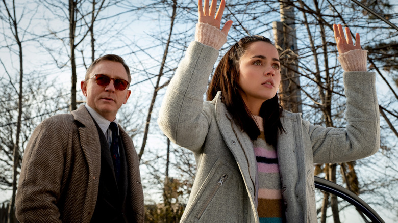 Marta Cabrera holding her hands up while Benoit Blanc stands behind her wearing sunglasses in Knives Out (2019)