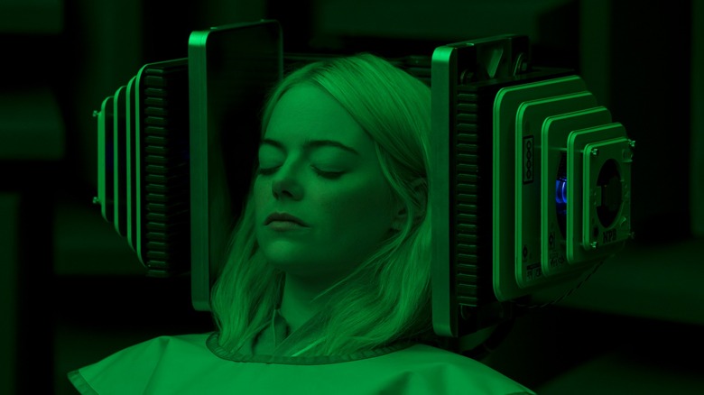 Annie, lit green, sitting back with a machine against her head