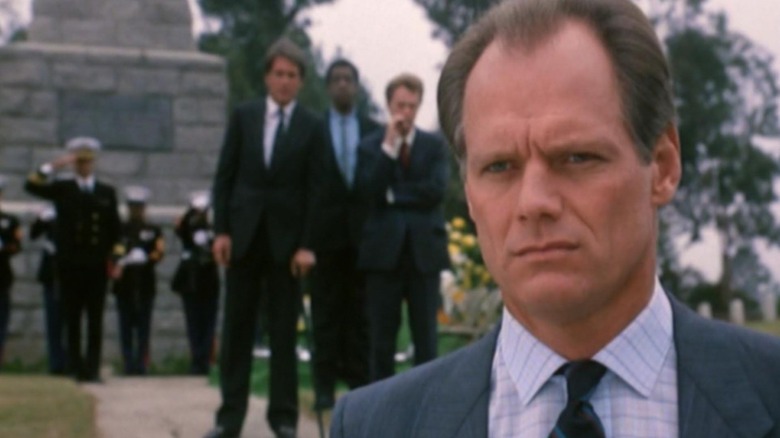 Hunter at a funeral with people behind him in Hunter (1984)