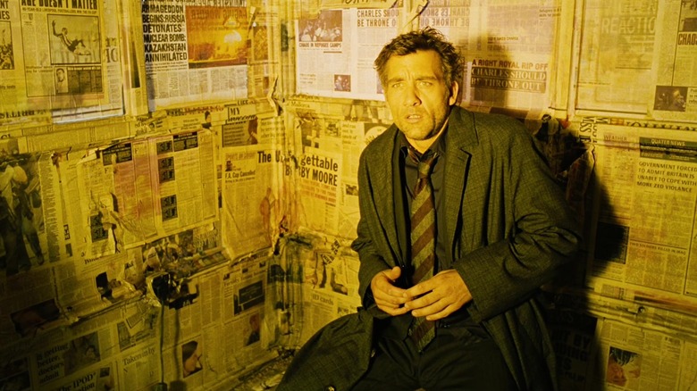 a light shines on Theo in a room lined with newspapers in "Children of Men" (2006)