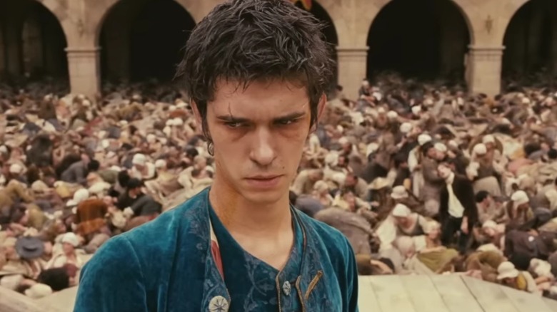 Jean-Baptiste Grenouille standing on a platform in the town square, as people writhe around on the ground around him, in "Perfume: The Story of a Murderer"
