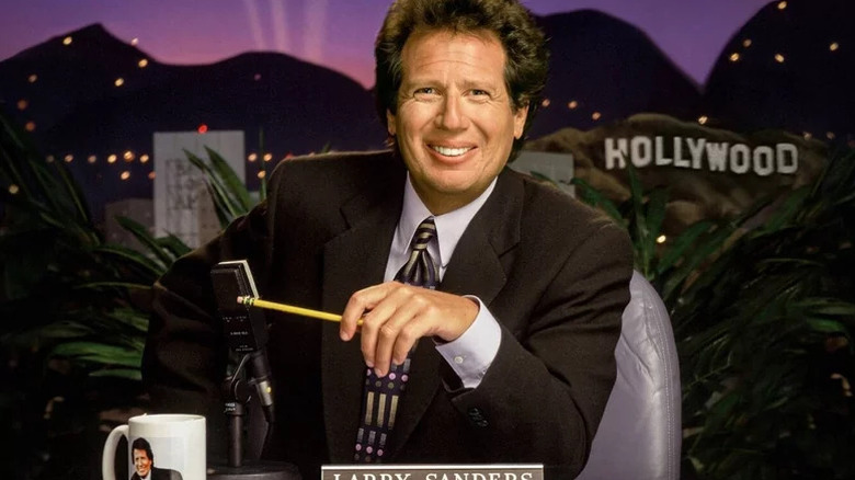 Larry Sanders grinning at his desk