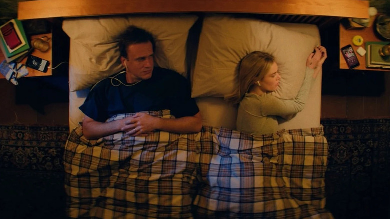 Dan and Lisa in bed wearing headphones in Over Your Dead Body