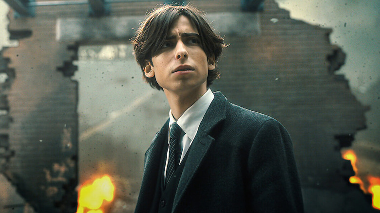 Number FIve standing in front of a broken wall in The Umbrella Academy