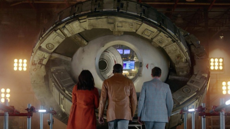 Three people facing a time portal in Timeless