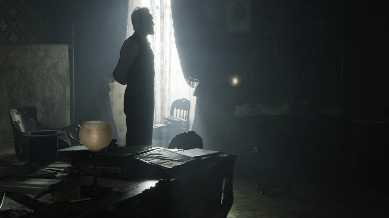 Abraham Lincoln standing in shadow by the window of his office in Lincoln