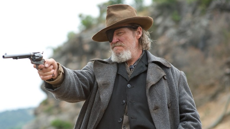 Rooster Cogburn aiming a revolver from atop a horse in "True Grit" (2010)