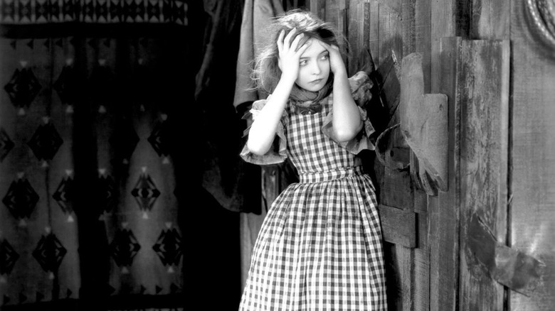 A tormented Letty clutching her head in The Wind (1928)