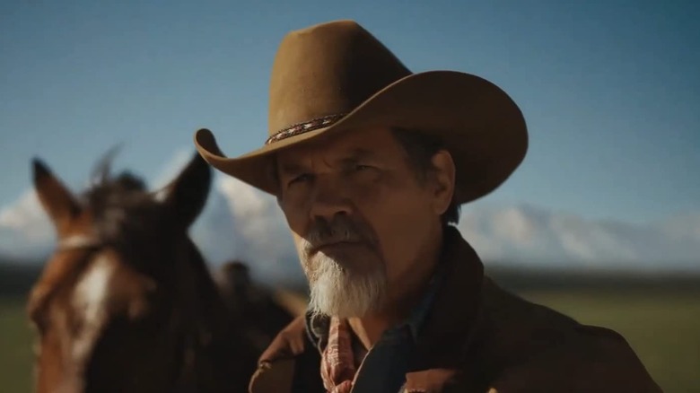 Royal looking at something standing in front of his horse on Outer Range