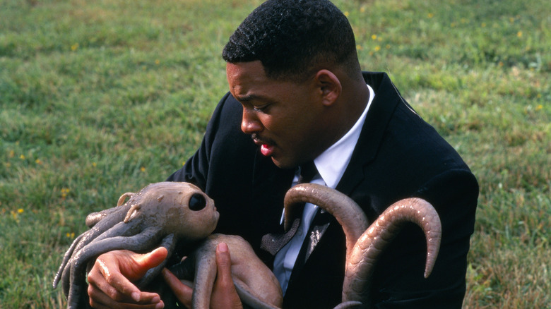 Agent J holding a newborn alien in Men in Black (1997)