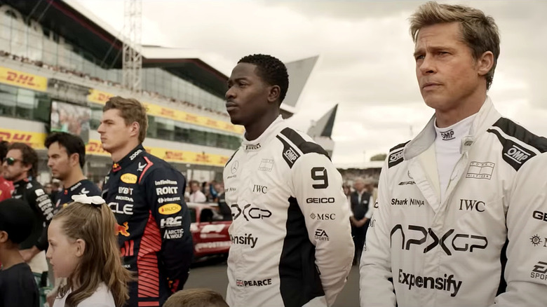 Racers and kids stand in a line on the track in "F1"