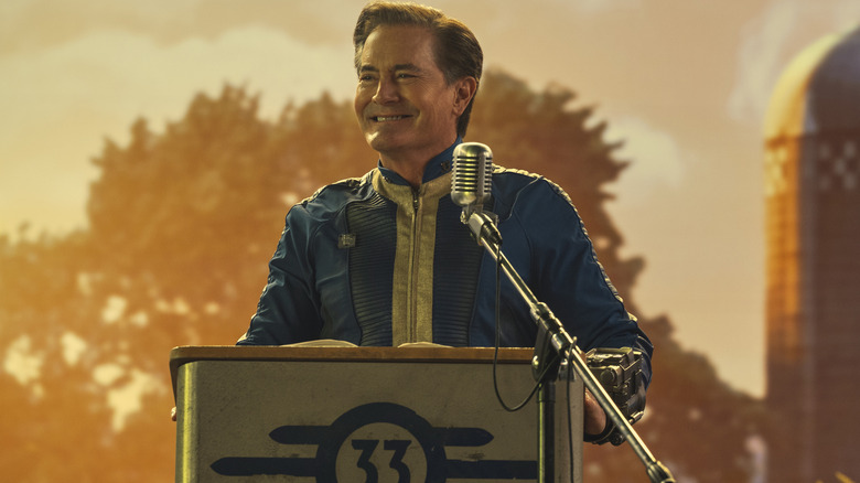 Hank MacLean smiling at a podium on Fallout