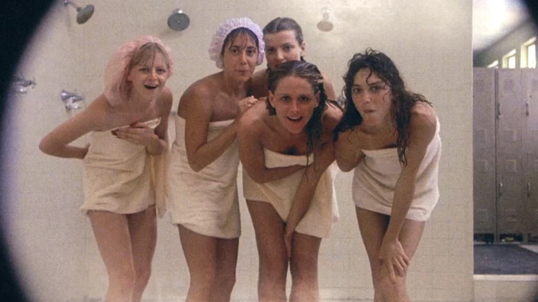 A group of women wrapped in towels are looking at the camera in a shower room in Porky's