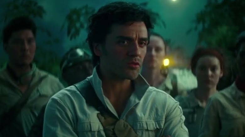 Poe Dameron crosses his arms while standing amongst the other Resistance members in a white shirt in "The Rise of Skywalker"