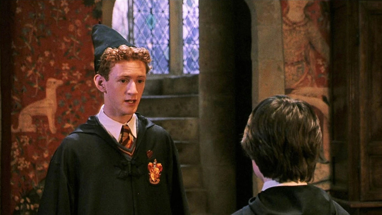 Percy Weasley addressing Harry (facing away) as a prefect in the Gryffindor common room