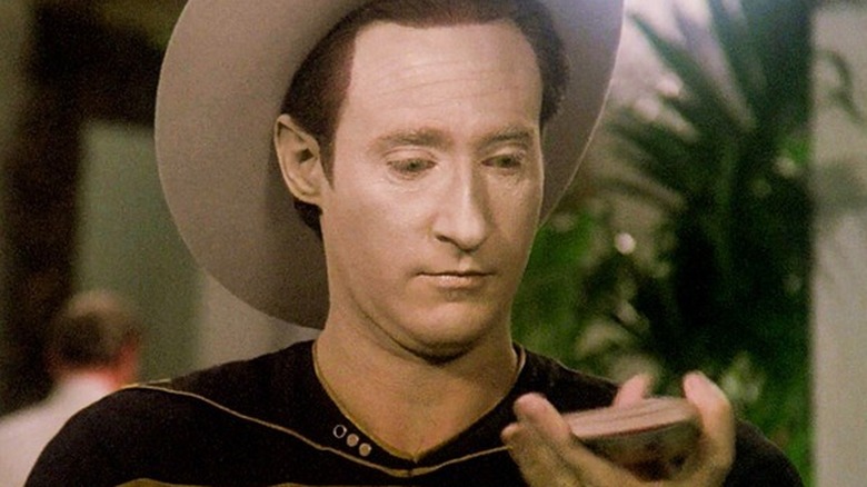 Data wearing a cowboy hat and holding a deck of cards in Star Trek: The Next Generation