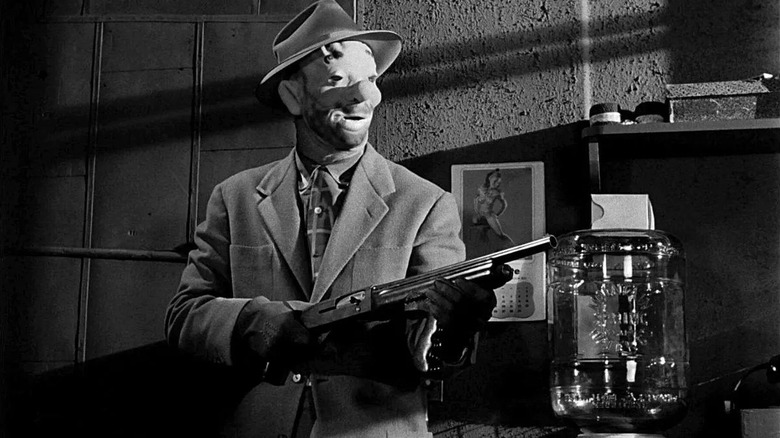 Masked robber holding up a gun in The Killing (1956)