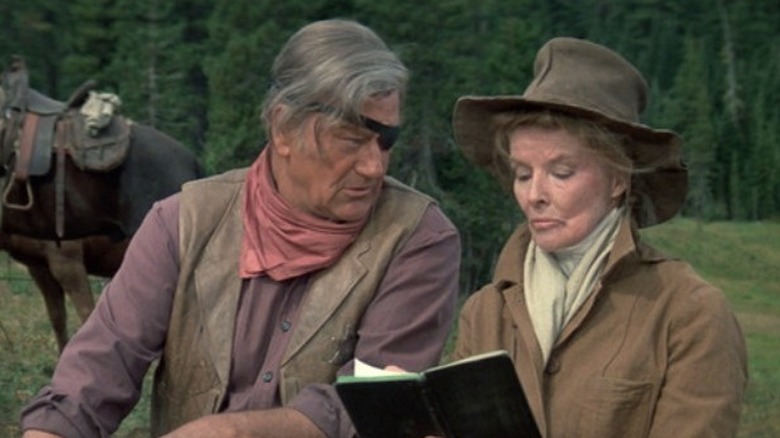 Rooster (John Wayne) and Eula (Katharine Hepburn) sitting together in "Rooster Cogburn."