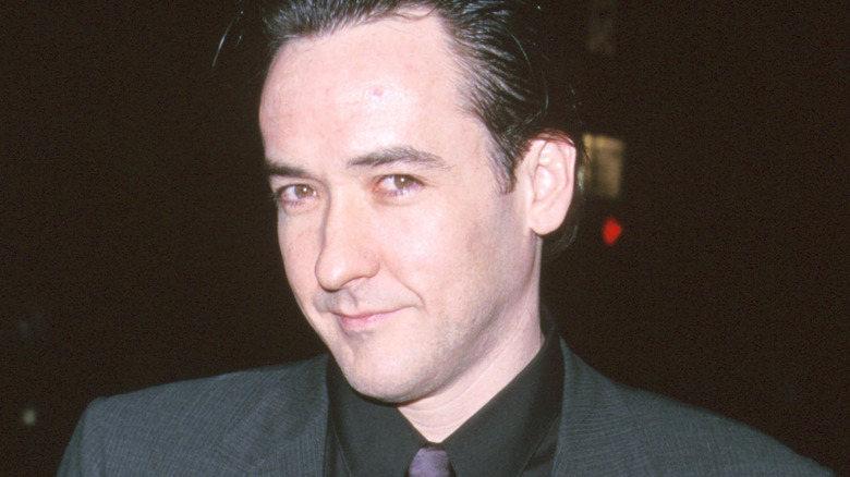 John Cusack smiling in a suit