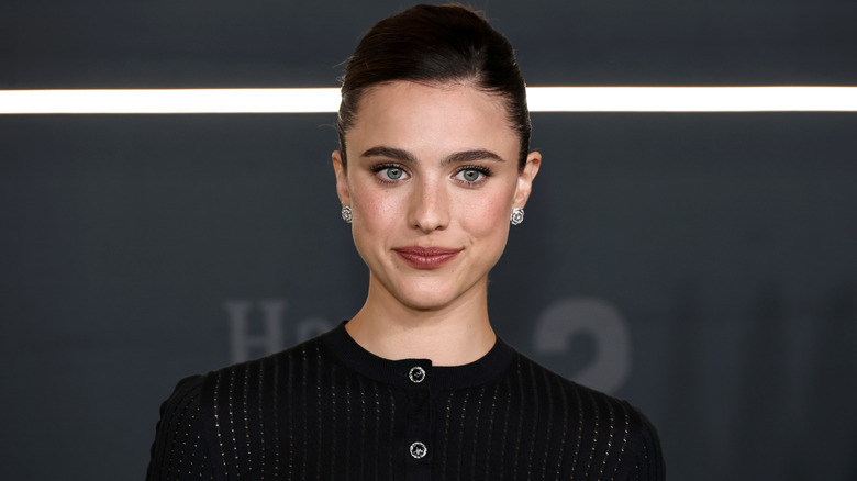 Margaret Qualley smiling in a black sweater