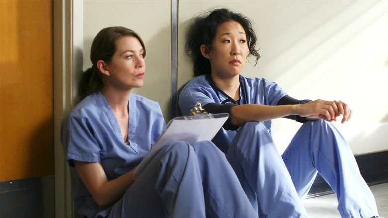 Meredith Grey and Cristina Yang sitting in the hospital hallway in Grey's Anatomy (2005)