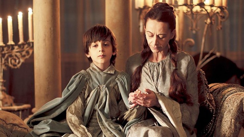 Robin and Lysa Arryn sitting on a chase together holding hands on Game of Thrones