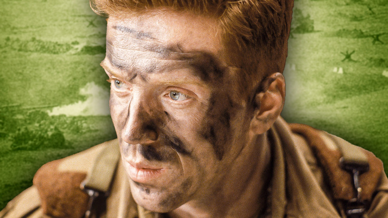 Dick with dirt on his face in Band of Brothers and a green background