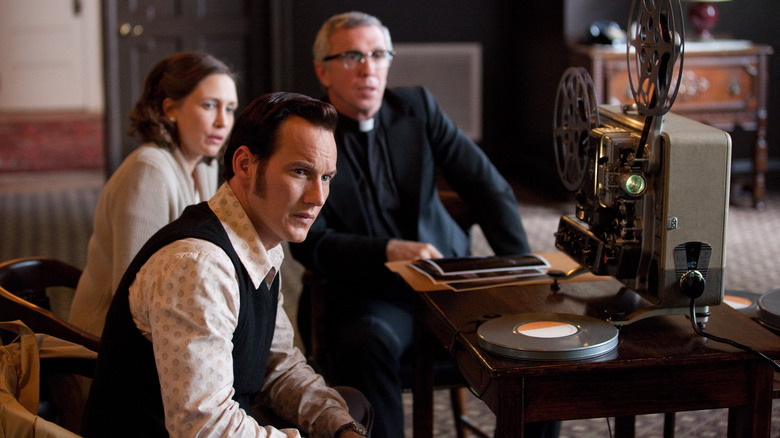 Ed and Lorrain Warren watching old footage with a priest in "The Conjuring"