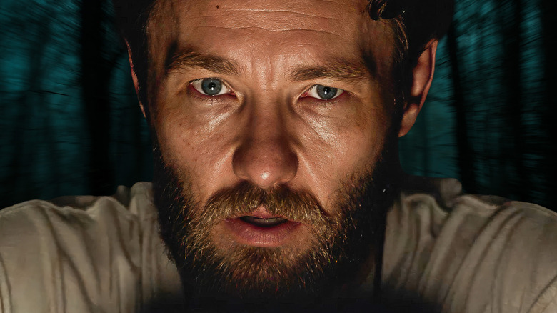 Paul from It Comes at Night against a forest backdrop