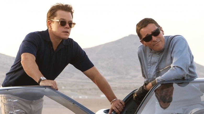 Carroll Shelby and Ken Miles leaning on a car and wearing sunglasses in Ford v Ferrari