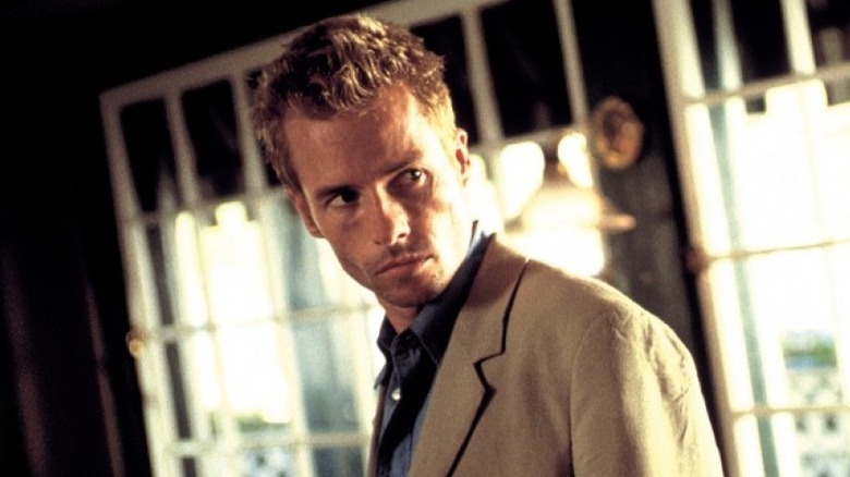 Leonard Shelby looking over his shoulder nervously in a tan suit in "Memento" (2000)
