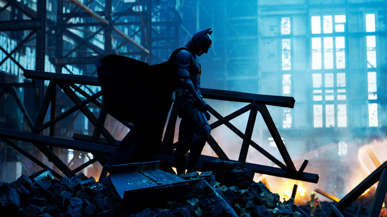 Batman standing solemnly in the wreckage of a burned-out building in "The Dark Knight" (2008)