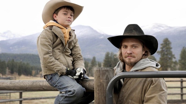 Tate (Brecken Merrill) sitting next to Kayce (Luke Grimes) on "Yellowstone."