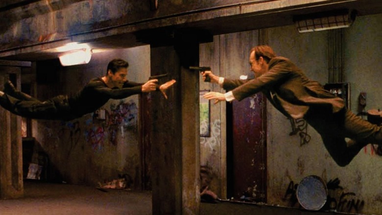 Neo and Agent Smith fly at each other with guns in "The Matrix" (1999)
