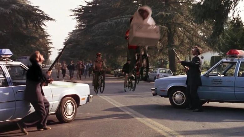 Elliot and E.T. take off while cops hold guns in E.T. the Extra-Terrestrial (1982)