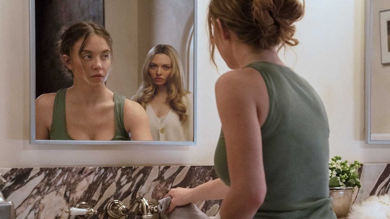 Millie cleaning the bathroom with Nina behind her in the mirror in The Housemaid