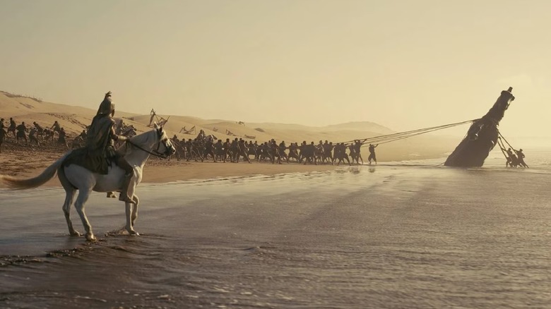 Men dragging the horse off the beach in The Odyssey