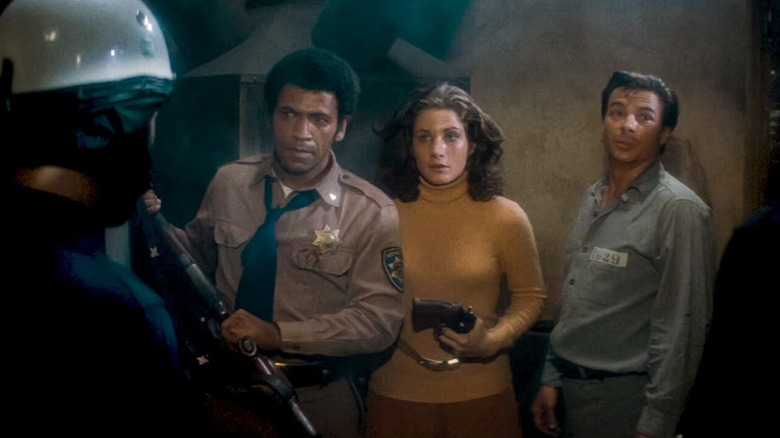 Bishop, Wilson, and Leigh talking to a helmeted police officer, all holding weapons, in Assault on Precinct 13 (1976)