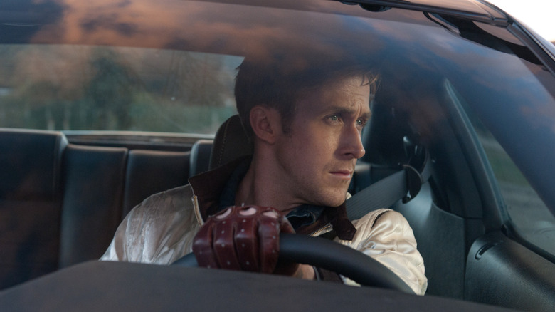 The Driver looking out the driver's side window of his car, red glove on the steering wheel, in Drive (2011)