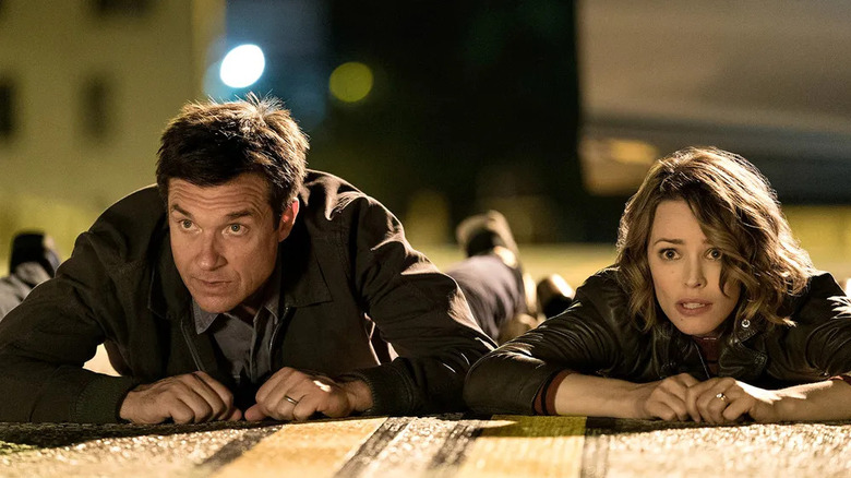 Max and Annie laying on the ground looking scared in Game Night