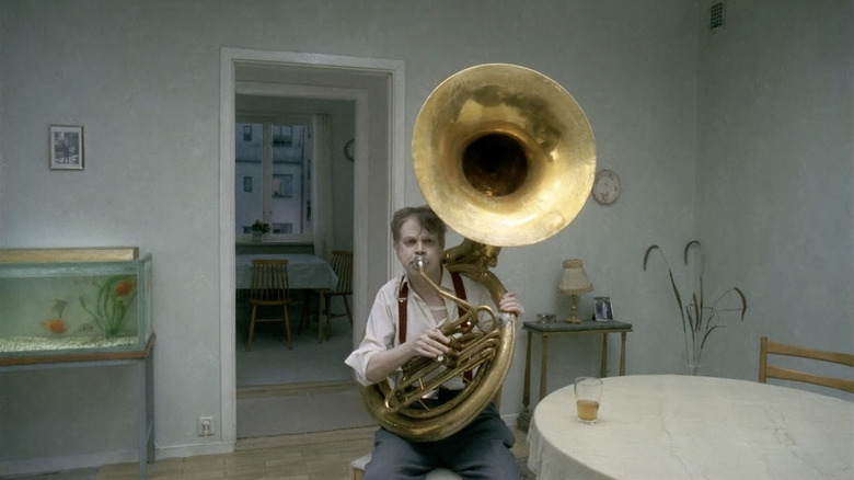 A man plays a tuba at his dinner table in You, The Living (2007)