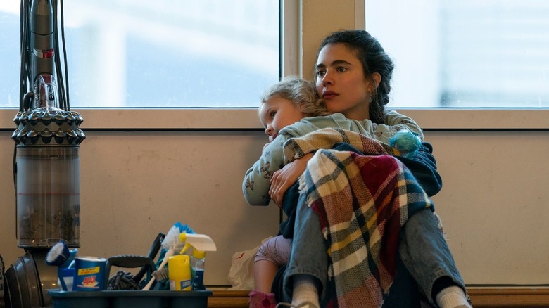 Alex sitting on the floor holding Maddy in Maid