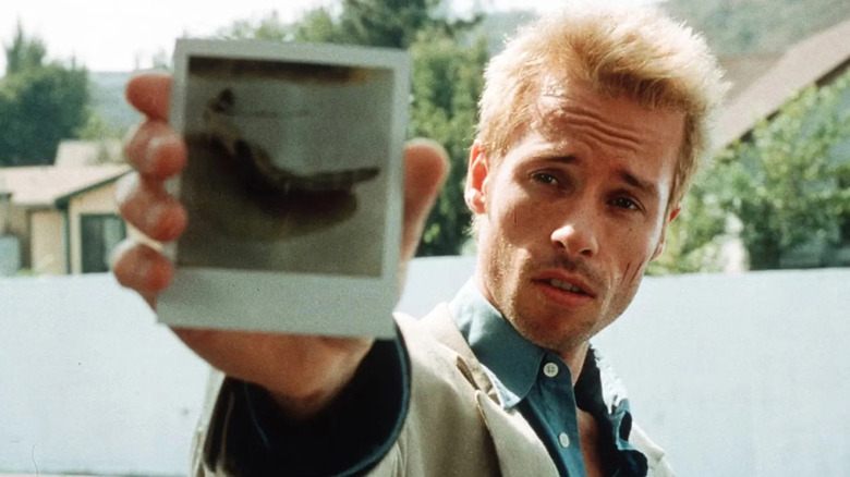 Leonard holding up a polaroid photo in 