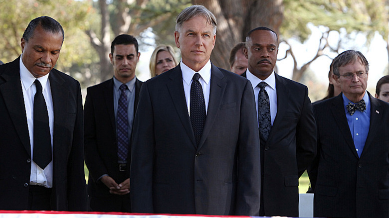 NCIS characters dressed in suits at a funeral scene