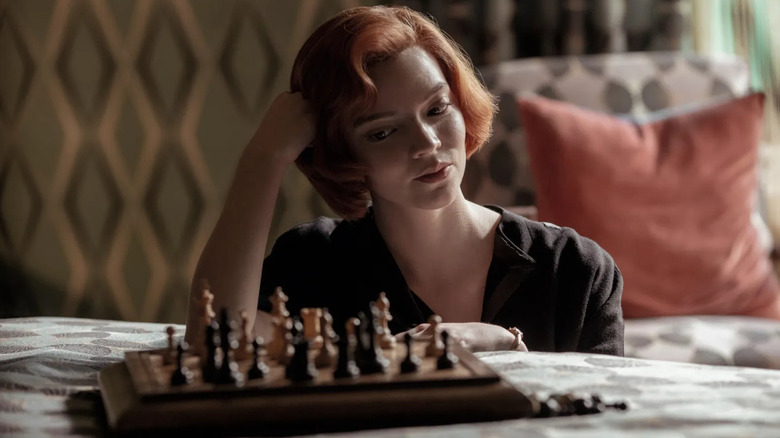 Beth sitting in front of a chess board on The Queen's Gambit